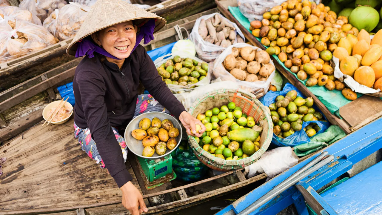 Händlerin mit Obst auf einem Boot am schwimmenden Markt im Mekong-Delta