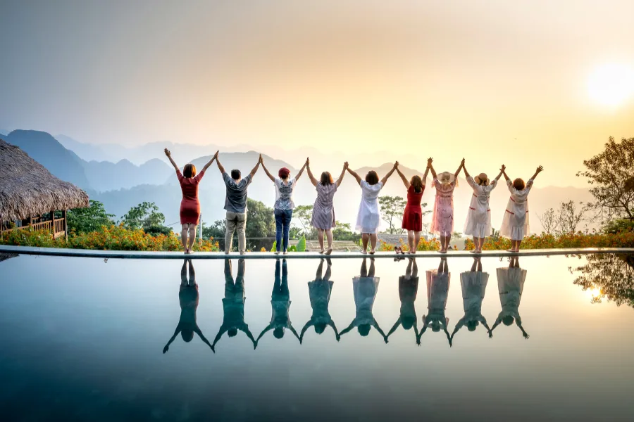 Gruppe springt fröhlich bei Sonnenuntergang am Pool – Urlaubsfreude mit Star Reisen