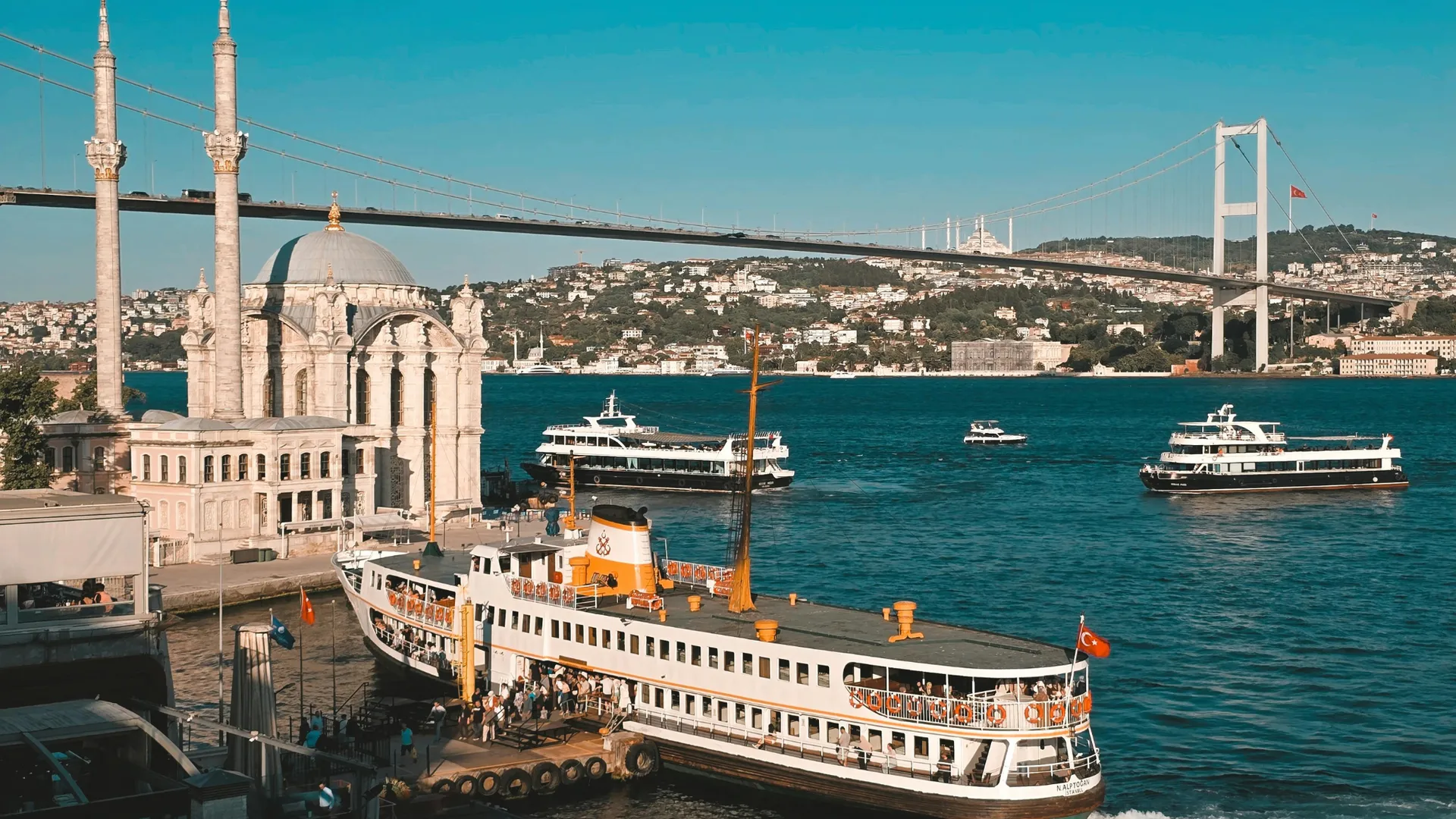 Ortaköy Moschee am Bosporus mit vorbeifahrenden Fährschiffen